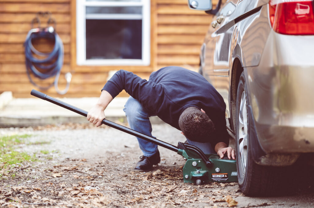 closeup shot of a man repairing a car with a tool
